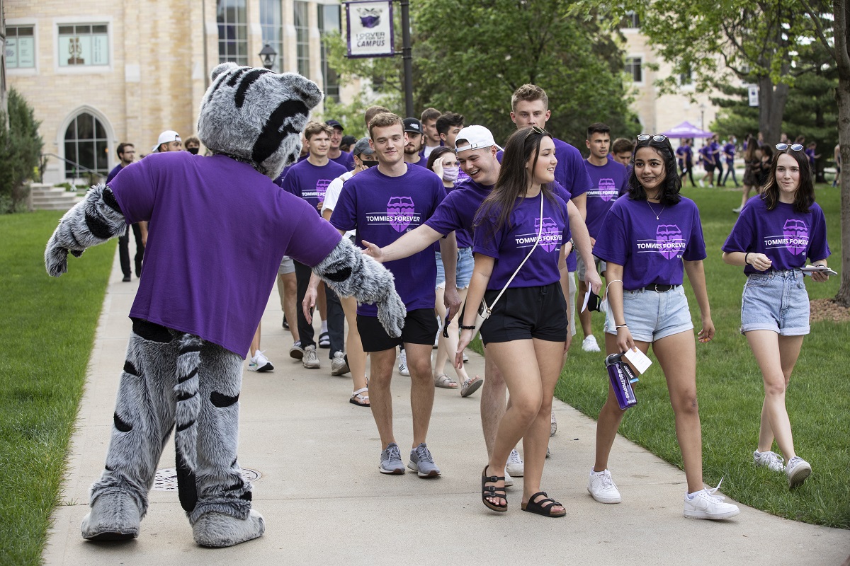 A group of students give the Tommie mascot high-fives