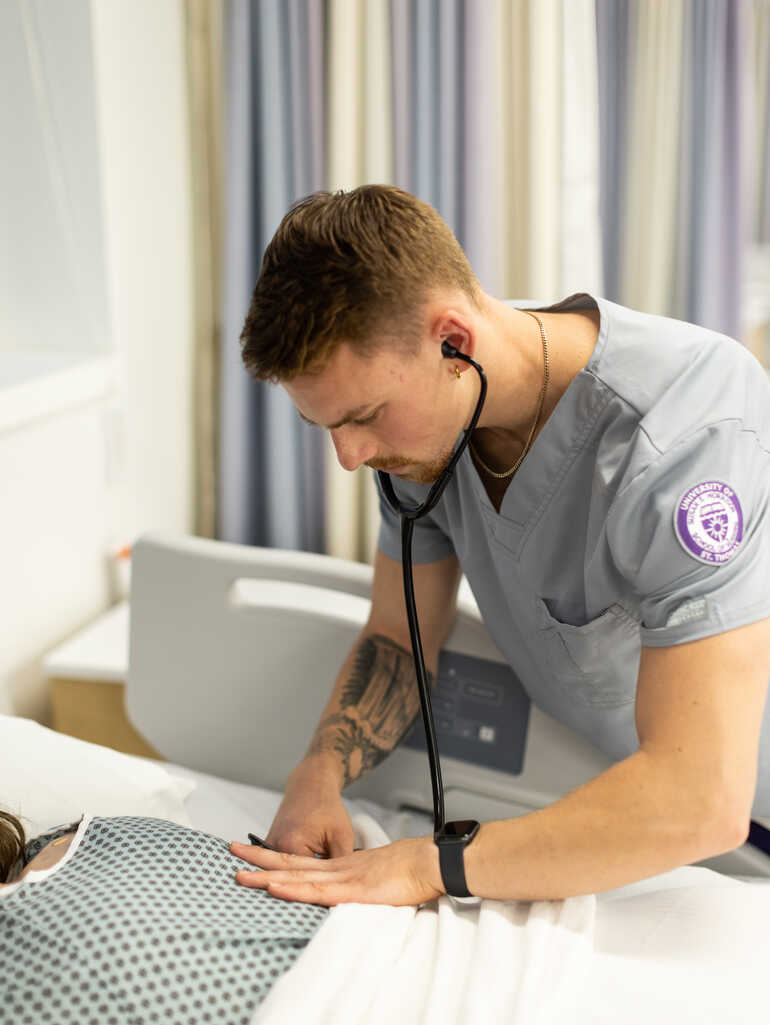A male nursing student works with a high-fidelity simulator