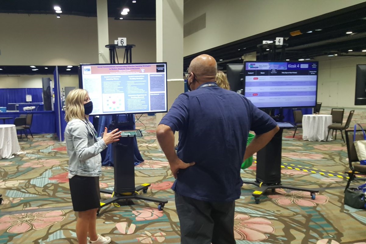 A presenter speaks to an audience in an exhibit hall at CSWE 2021.