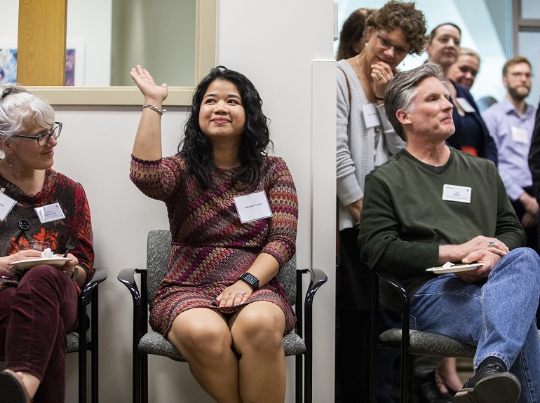 A woman raises her hand at a networking event.