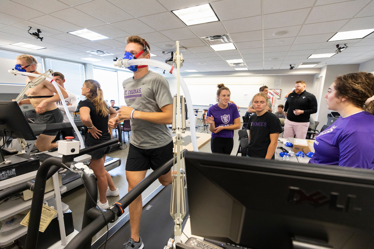 Students observe while athletes run on a treadmill
