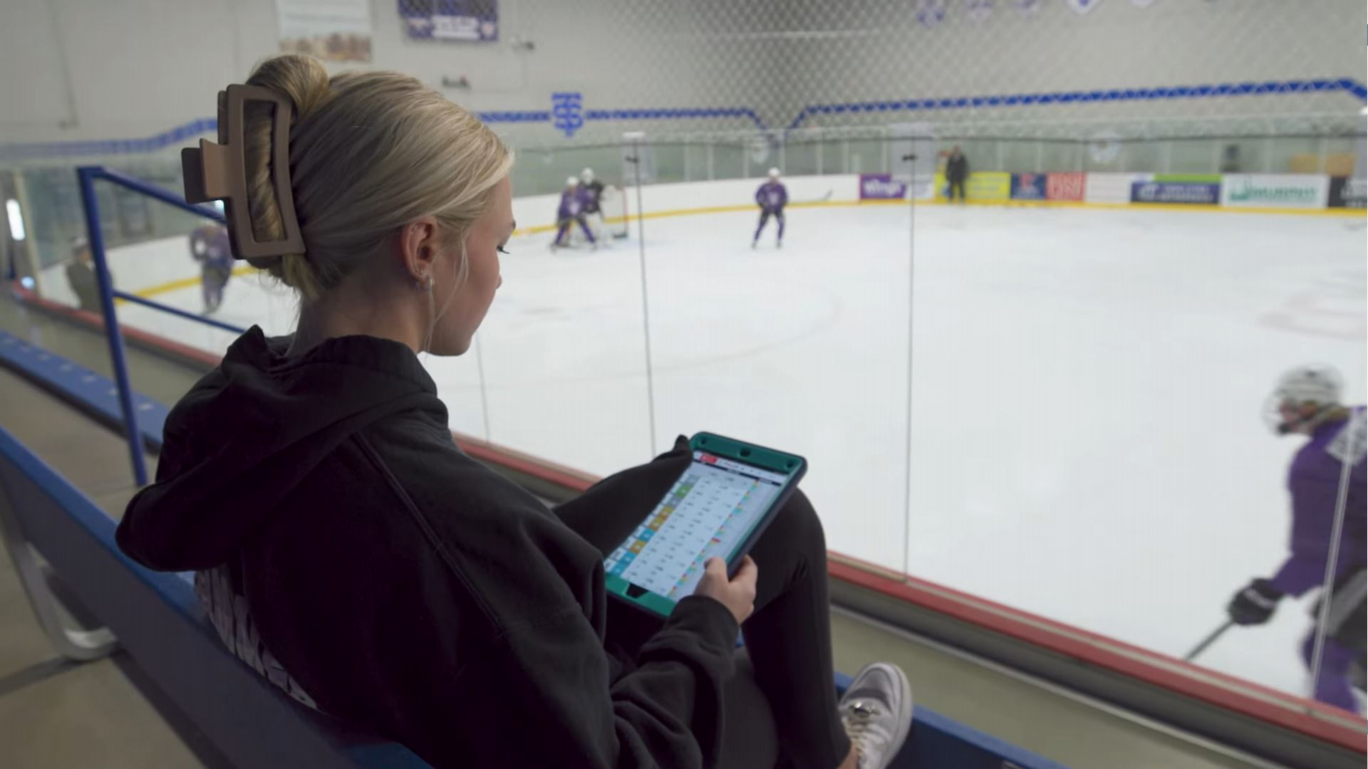 A female student with a tablet at a hockey rink
