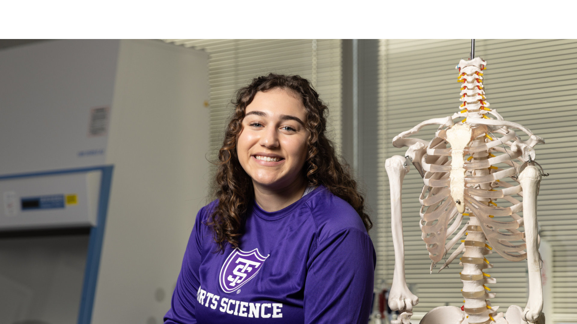 Student posing next to a skeleton