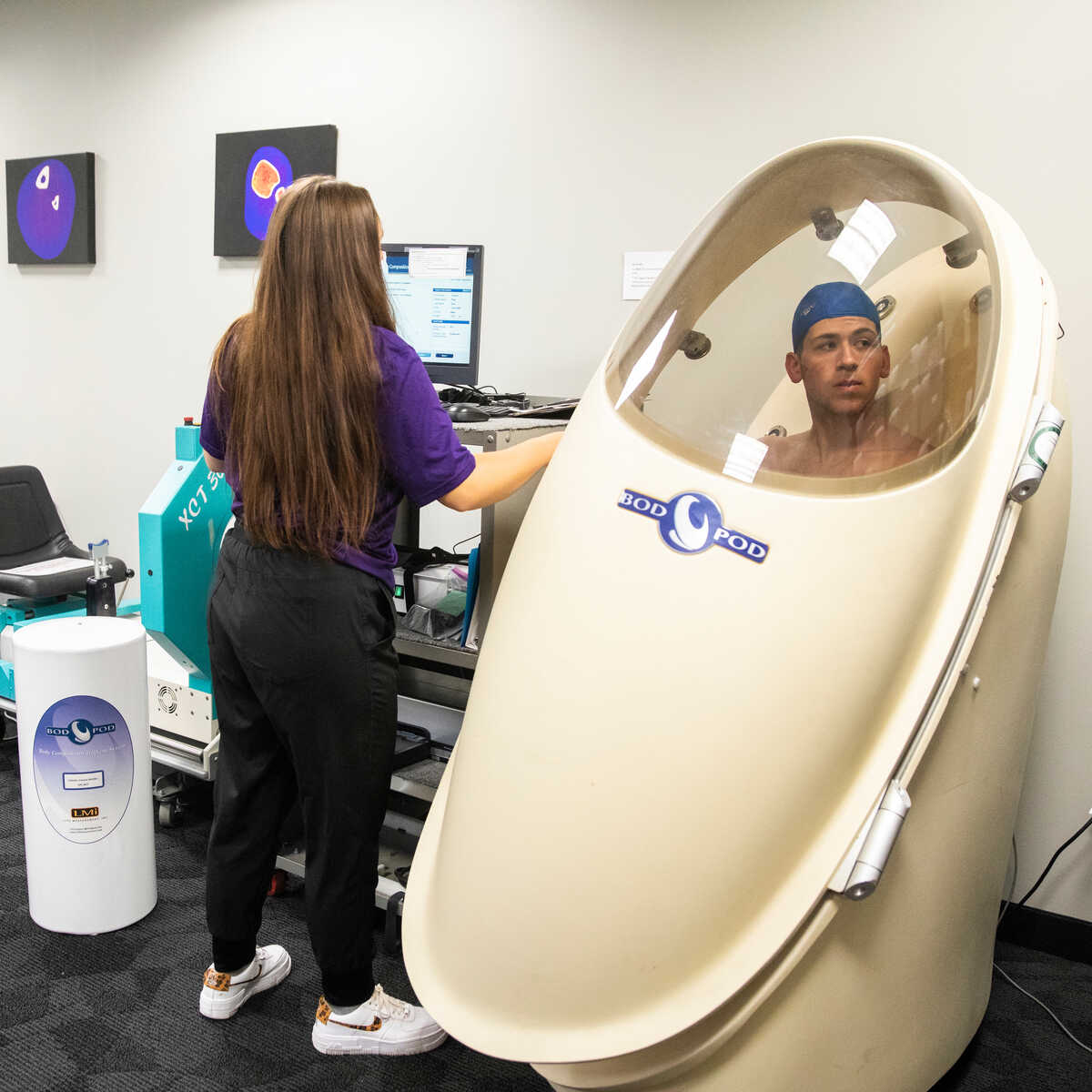A female student observes a male student in a Bod Pod