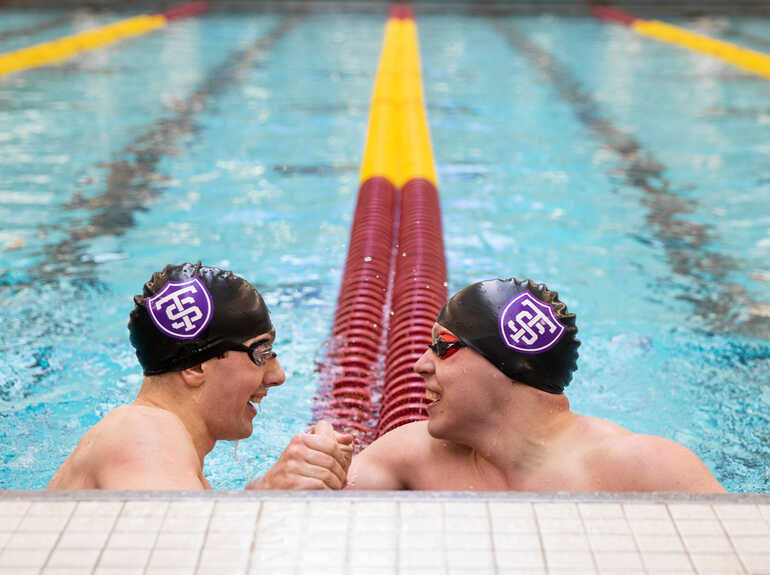 Two men clasp hands in a pool