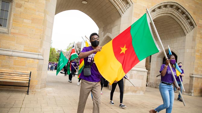student walking through the arches with flag