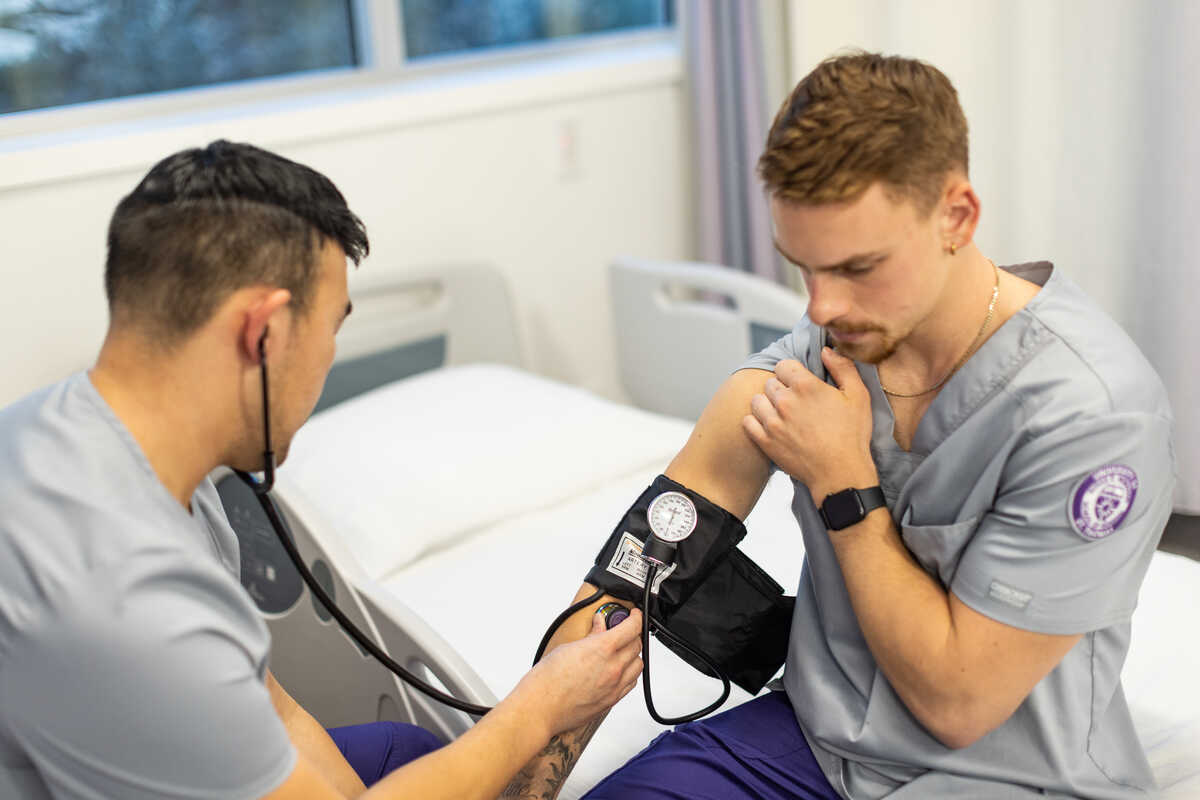 A male nurse takes the blood pressure of another male nurse