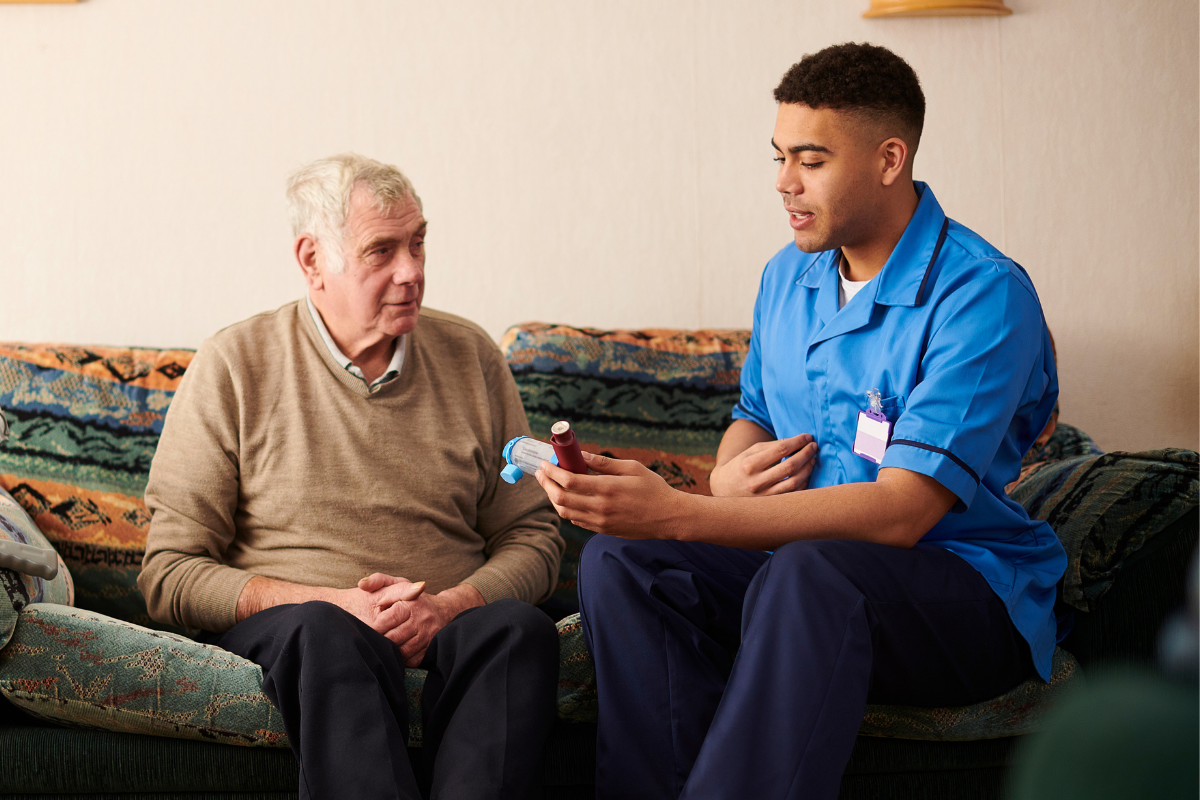 A male nurse speaks with an older adult in his home.