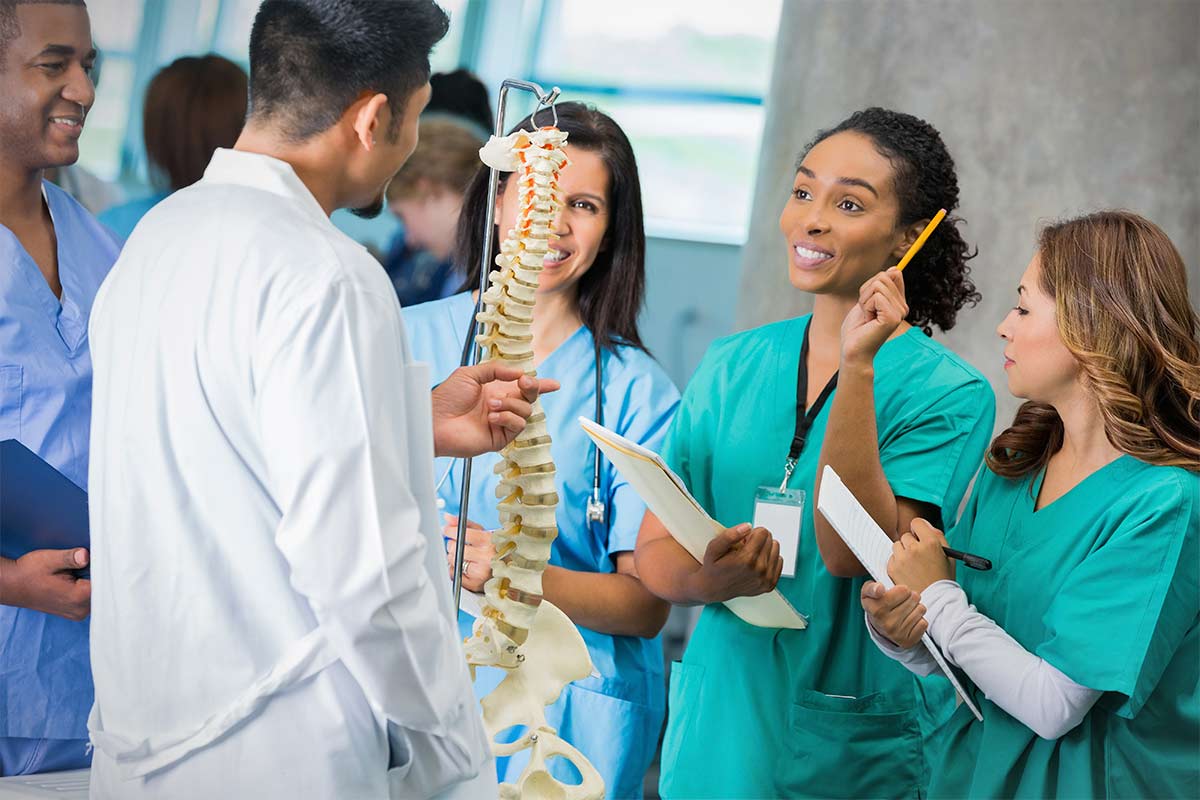 Doctors teaching interns with a skeleton of a spine.