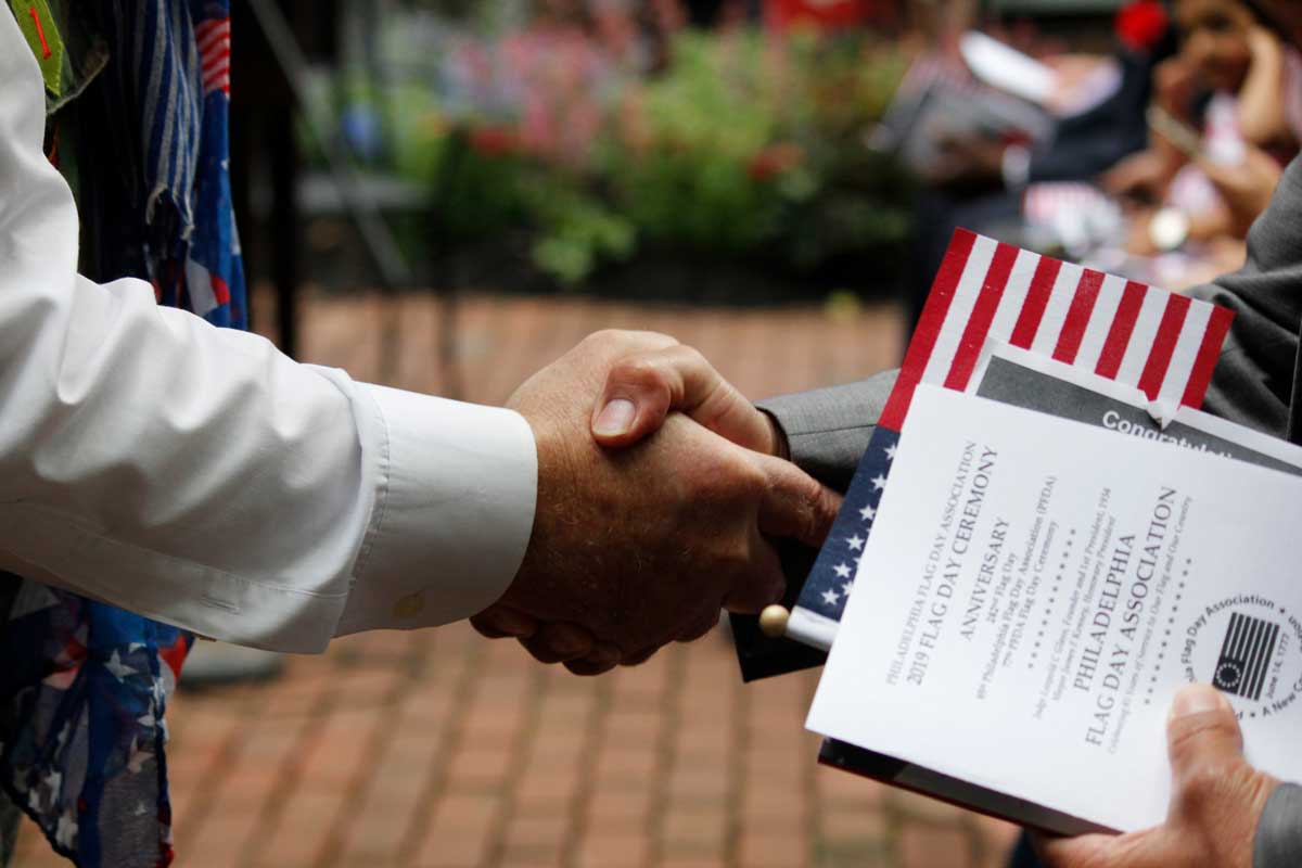 Two individuals shake hands at a naturalization ceremony