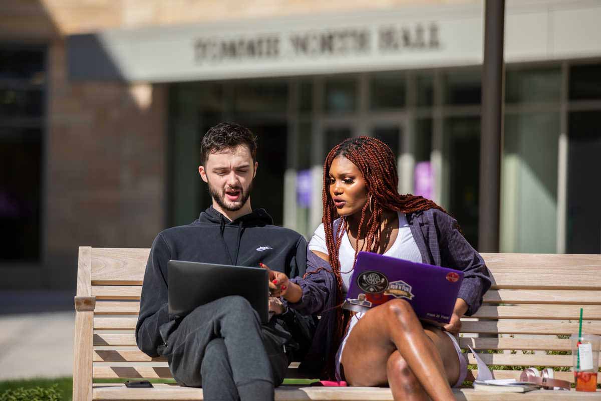 Two students working together outside on a bench