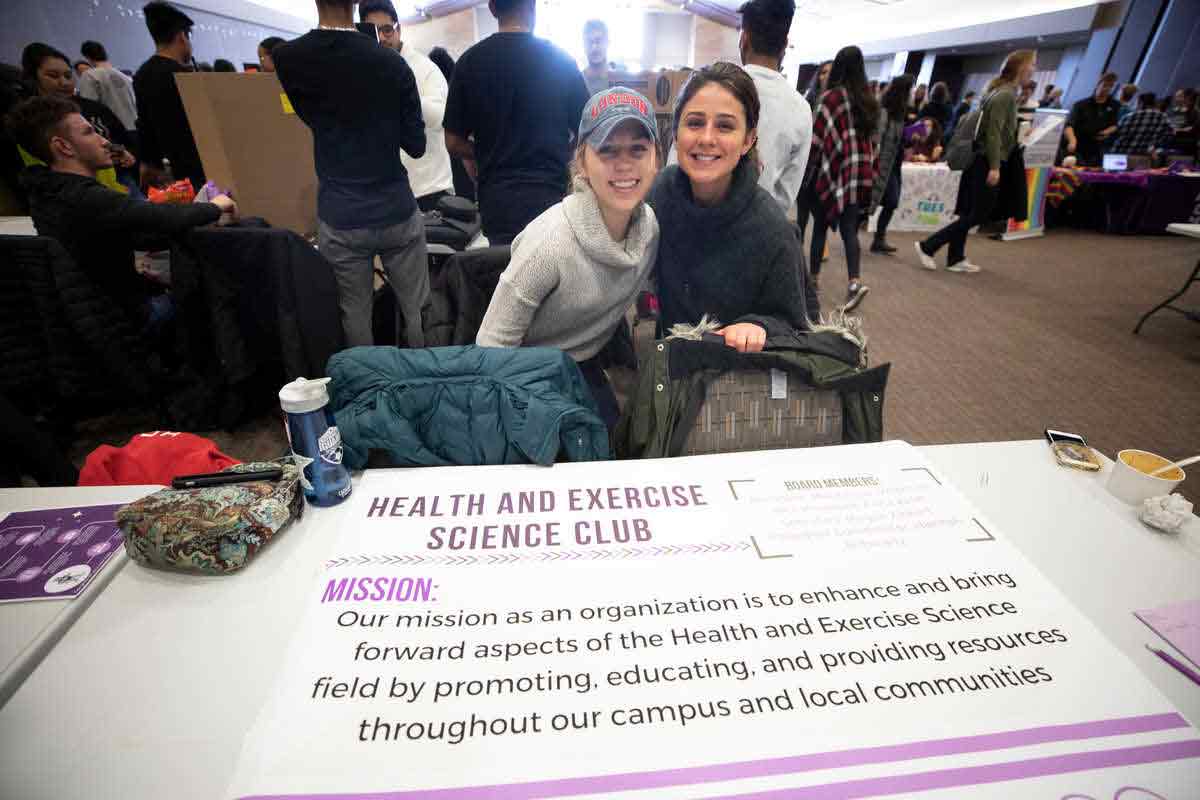 Two students sit at the HES club table at activities fair