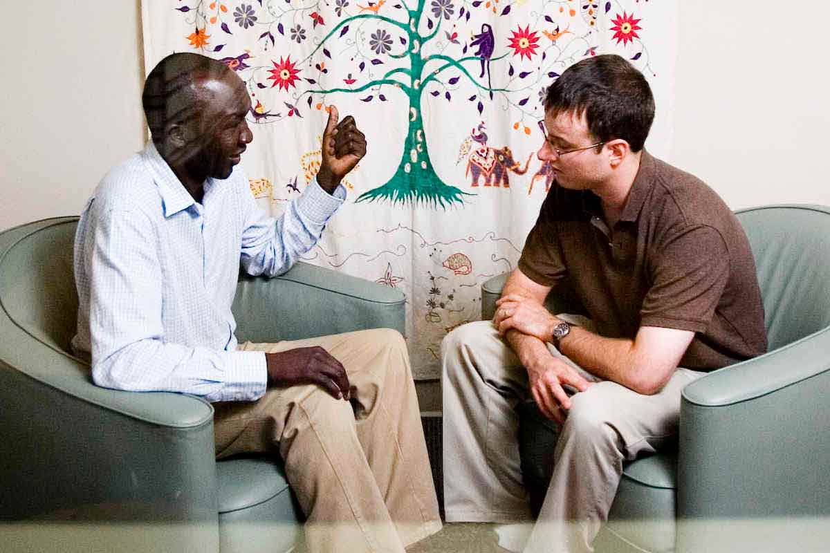 Two individuals sit together and talk