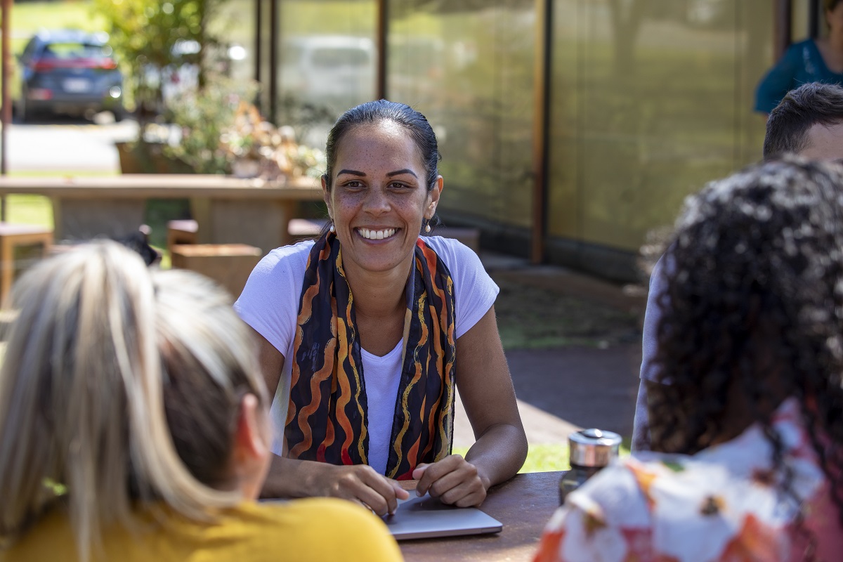 Students talk together around a table outdoors.