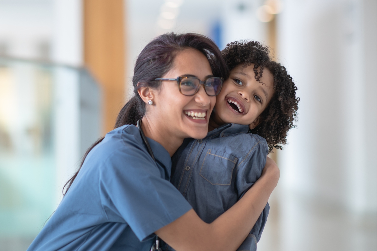 A female nurse hugs a smiling boy