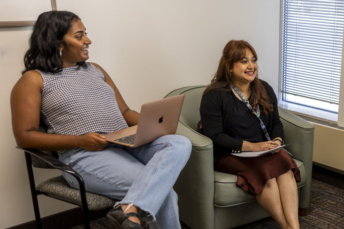 two people smiling and holding laptops