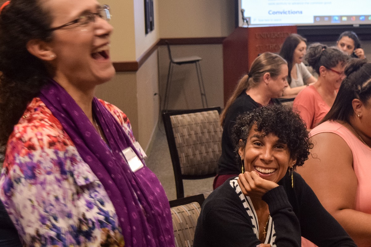 A student smiles while a professor laughs