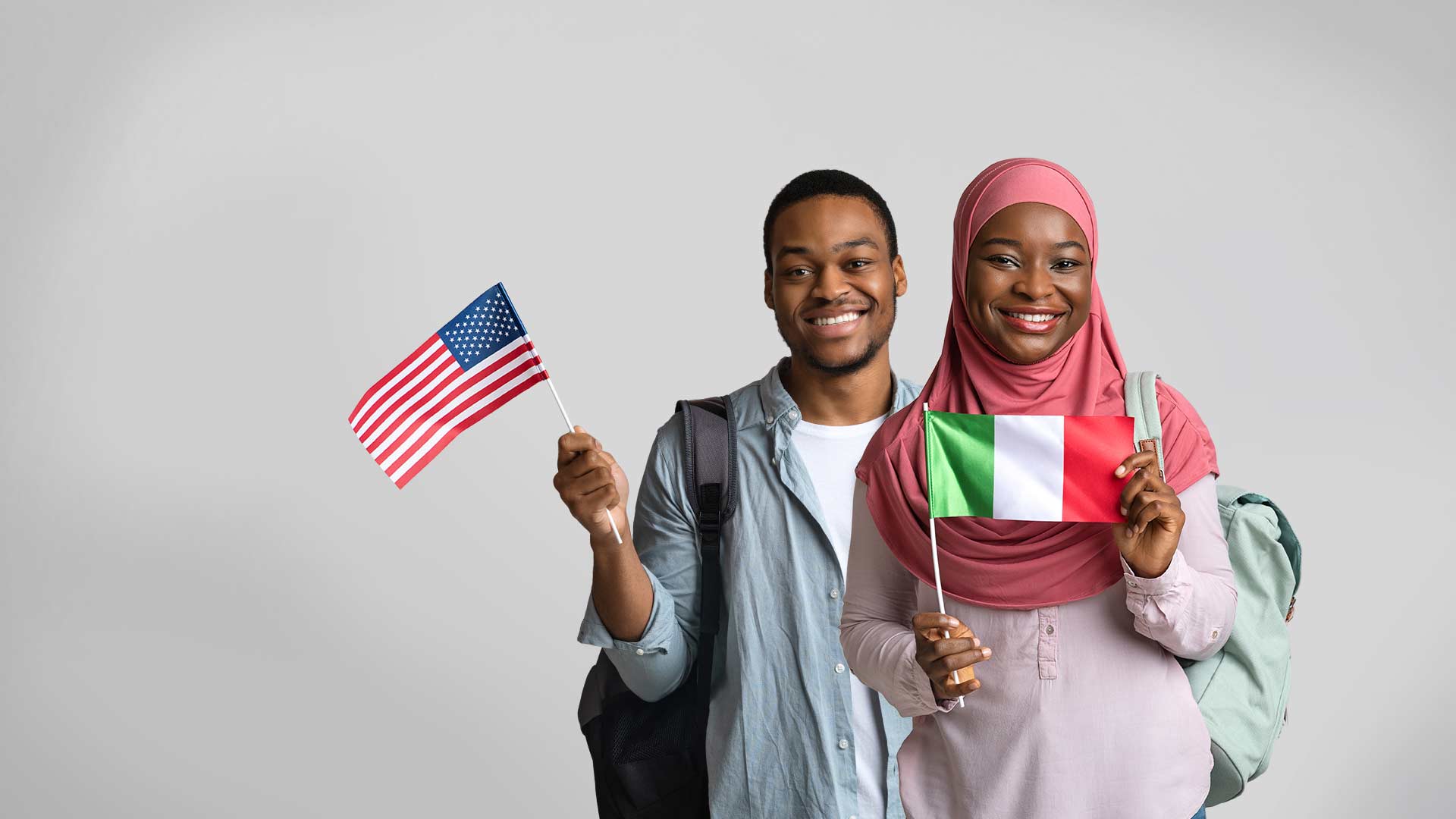 Two individuals stand holding two flags