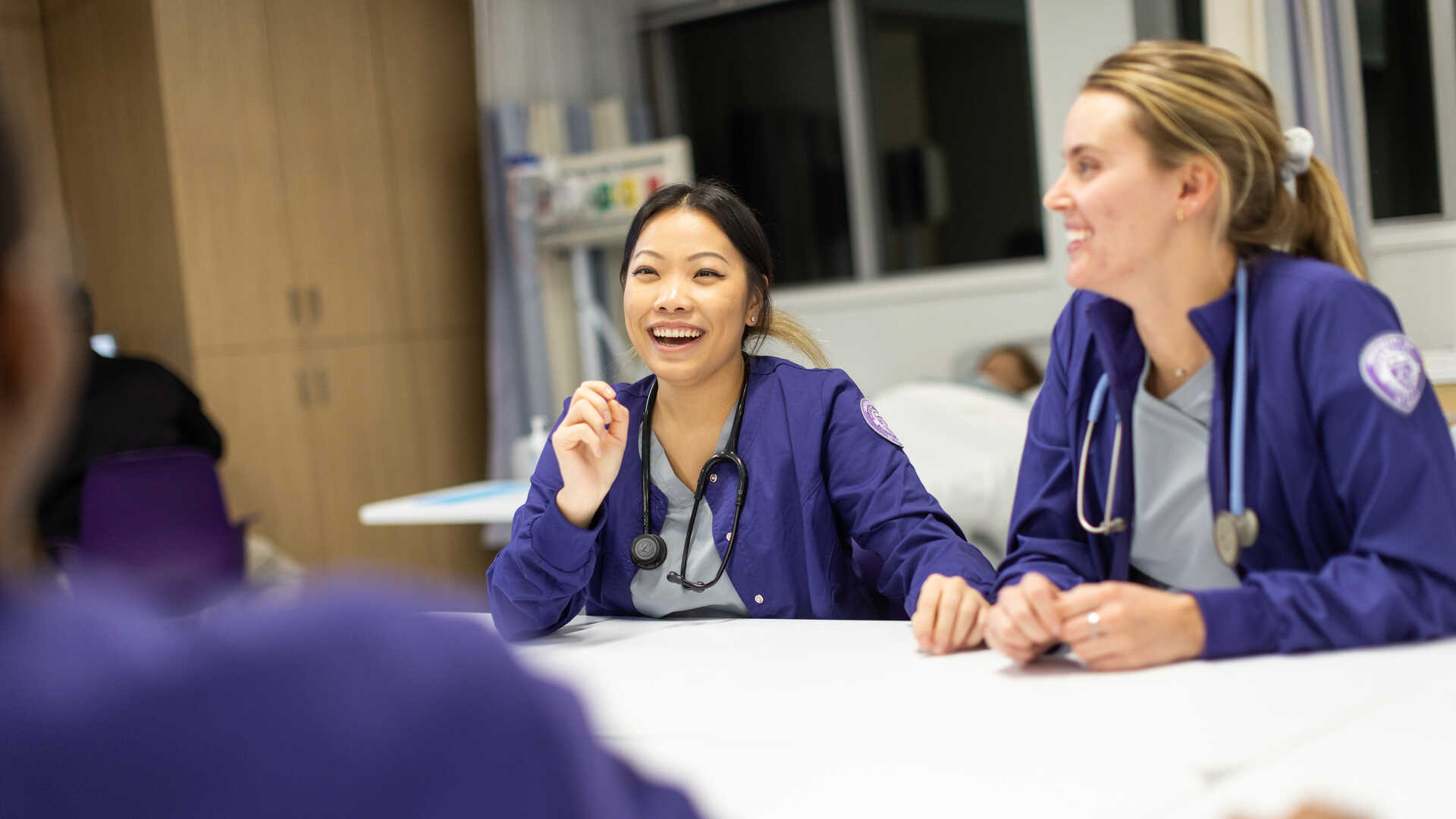 Two women in nursing scrubs in a classroom