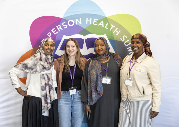 Four Students posing against event backdrop