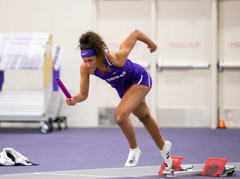 A woman runs with a baton on a track